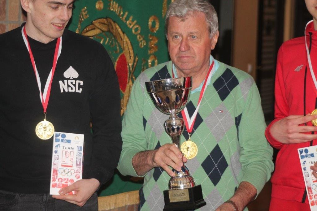 Trzej mężczyźni z medalami i pucharem na ceremonii