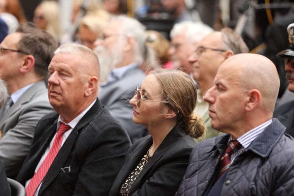 Grupa dorosłych słucha przemówienia na zewnątrz