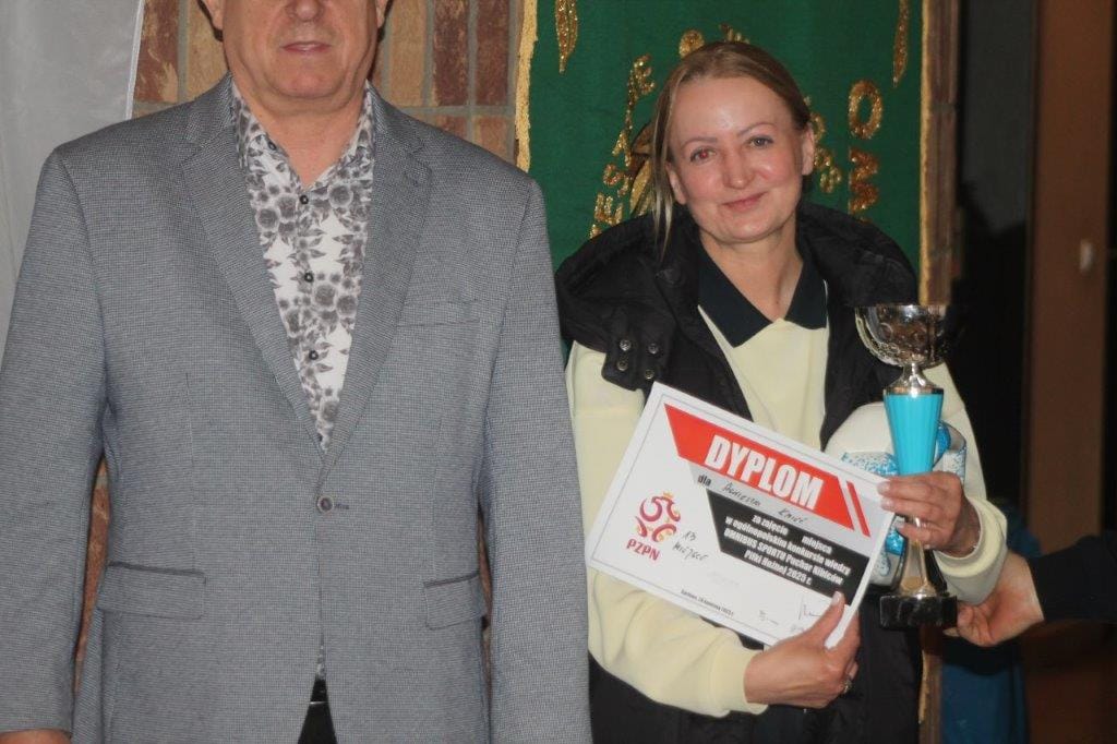 Kobieta odbiera dyplom i puchar od mężczyzny