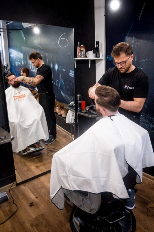 Fryzjer męski strzyże klienta w nowoczesnym salonie