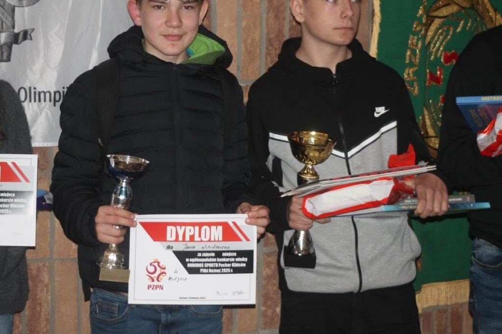 Dwóch młodych mężczyzn trzymających puchary i dyplomy