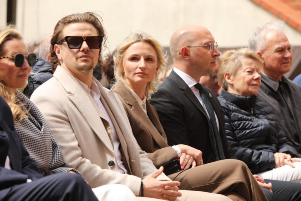 Grupa ludzi siedzi na uroczystości na zewnątrz