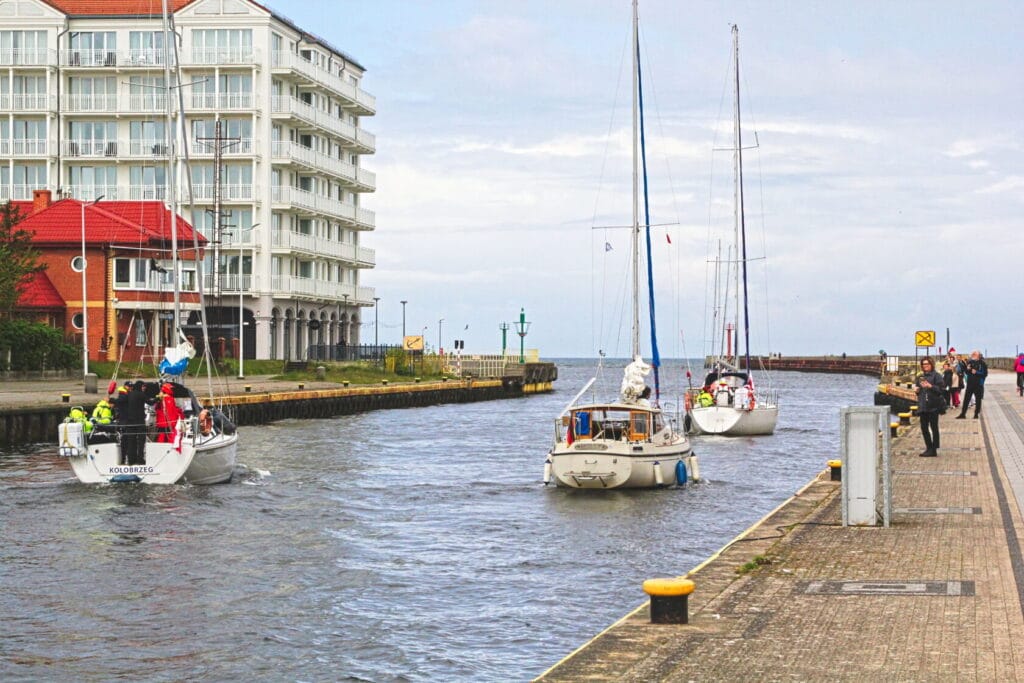 Żaglówki wpływające do portu przy nadmorskim bulwarze