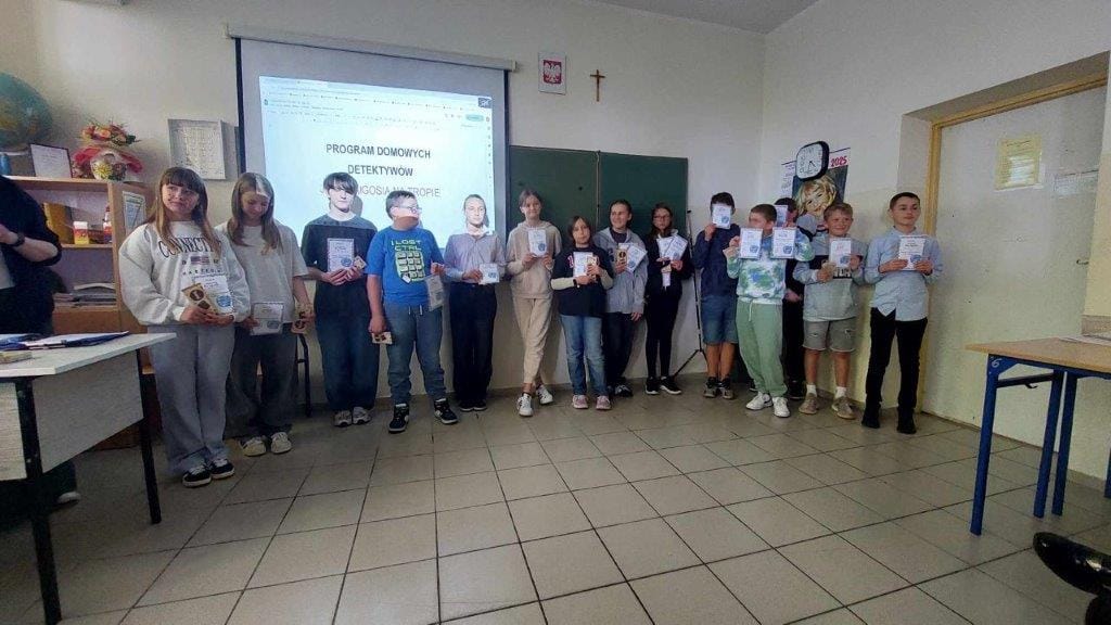 Grupa uczniów z dyplomami w sali lekcyjnej