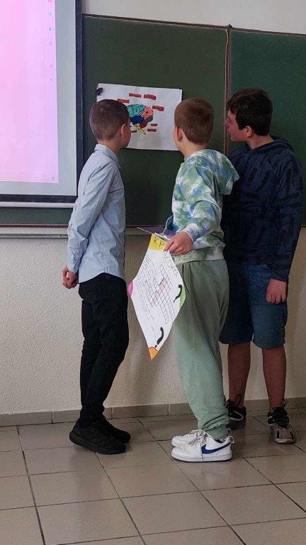 Uczniowie prezentują projekt na tablicy w klasie