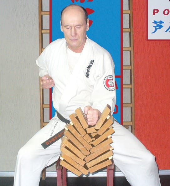 Karateka łamie cegły dłonią w dojo