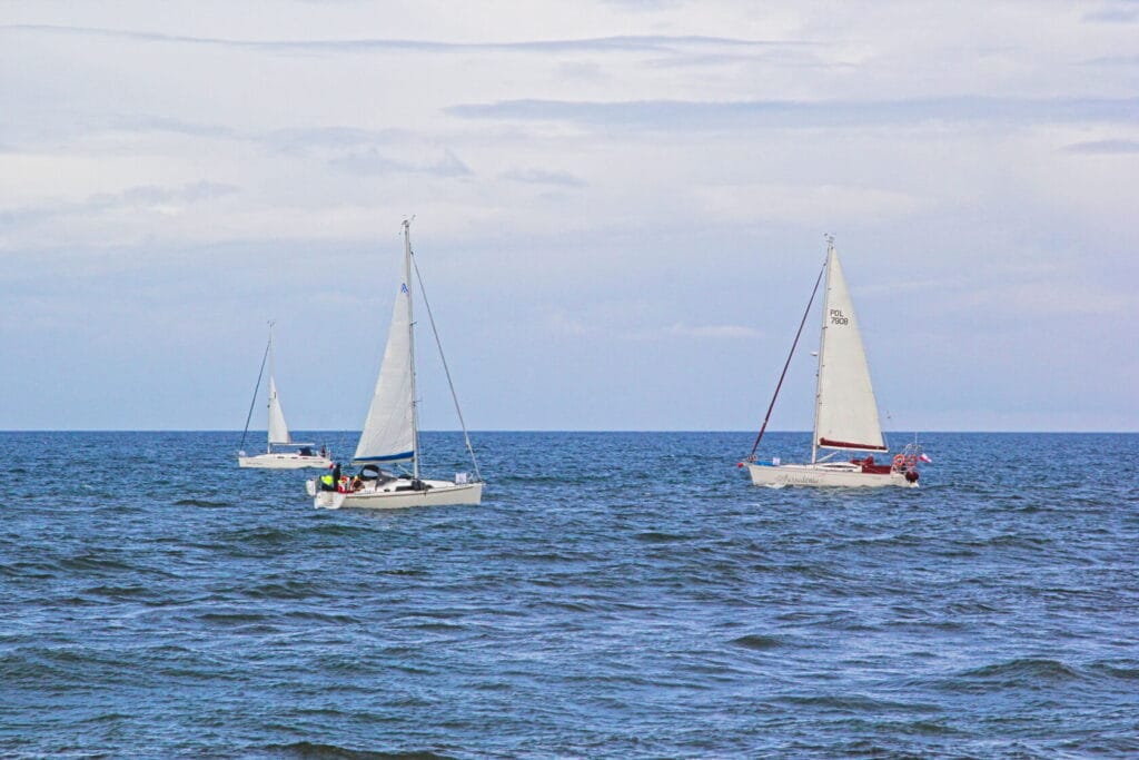 Trzy żaglówki pływające na otwartym morzu