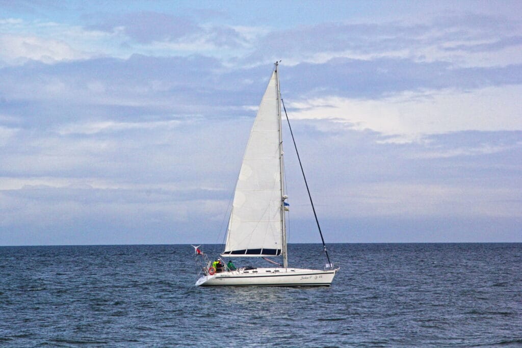 Łódź żaglowa płynie na tle chmurzastego nieba