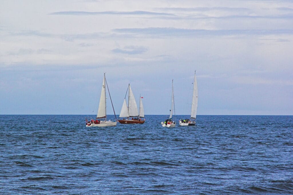Żaglówki płynące po morzu, niebo zachmurzone
