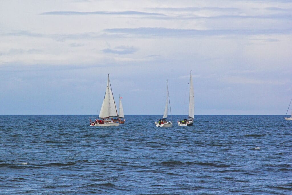 Żaglówki płynące na otwartym morzu, chmury