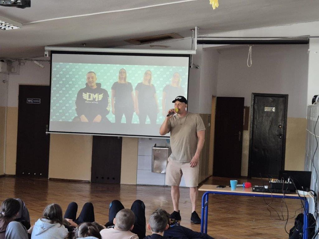 Prezentacja na scenie z mężczyzną śpiewającym do mikrofonu