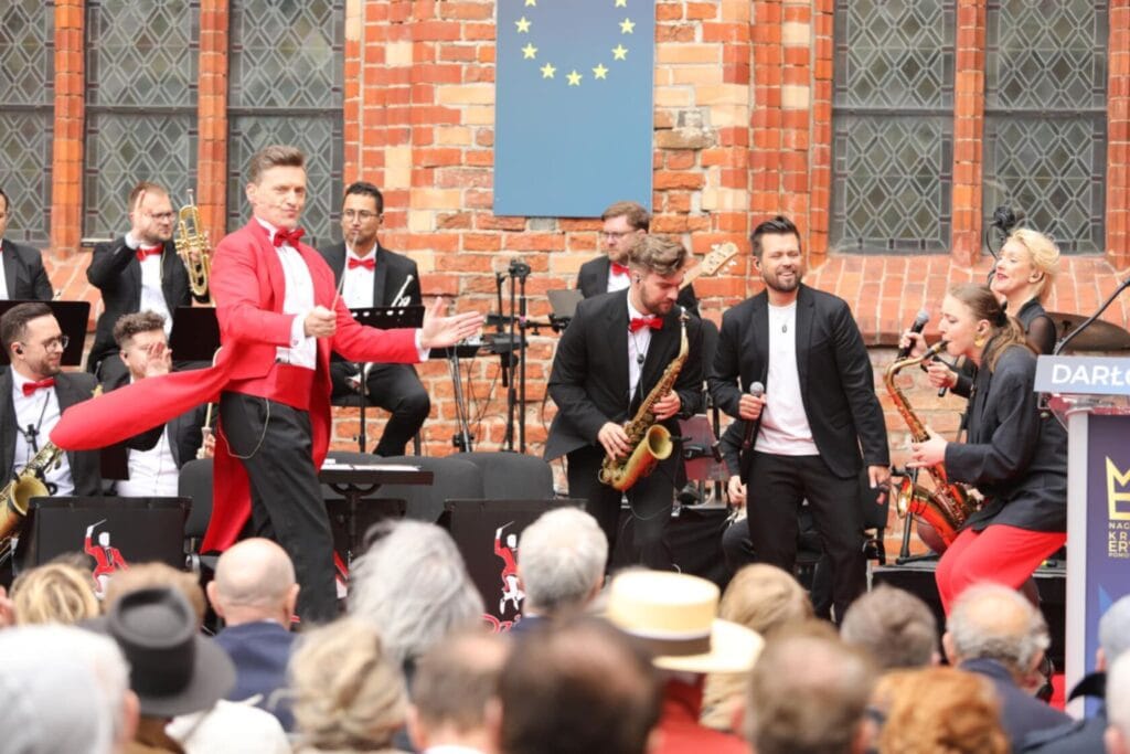 Koncert na żywo z orkiestrą i tancerzem w czerwonym płaszczu