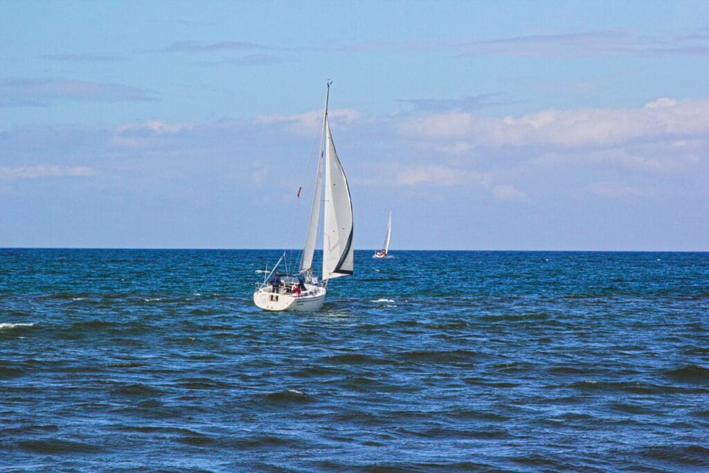 Żaglówki na falującym morzu pod niebieskim niebem