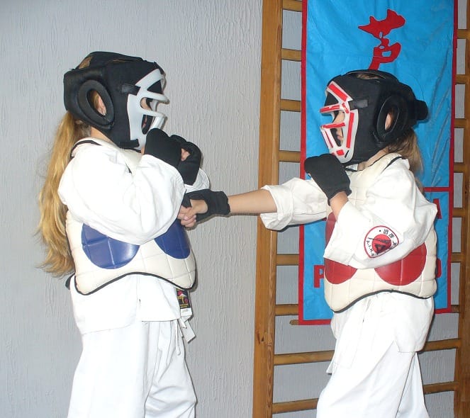 Dzieci w kimonach ćwiczą taekwondo.