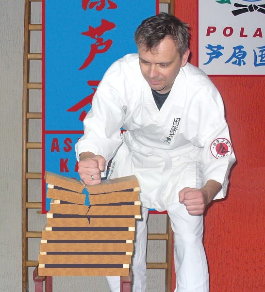 Karateka łamie deski podczas pokazu w dojo