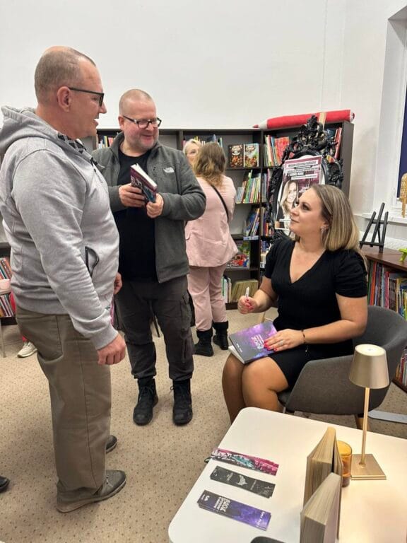 Kobieta autorka rozmawia z mężczyznami w księgarni