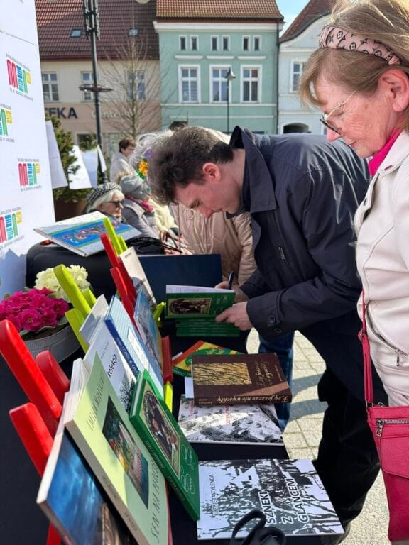 Ludzie przeglądają książki na stoisku na zewnątrz