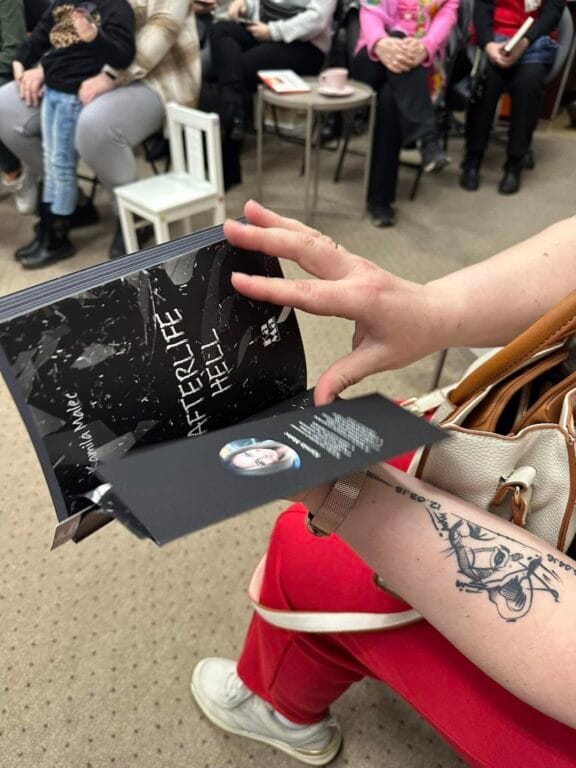 Osoba trzymająca broszurę z siedzącymi ludźmi w tle