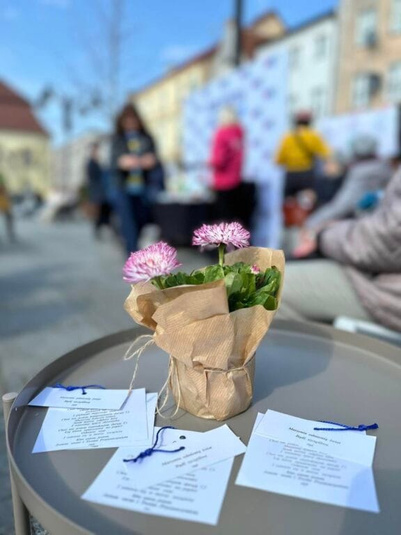 Kwiaty w papierowym opakowaniu na tle ludzi na wydarzeniu