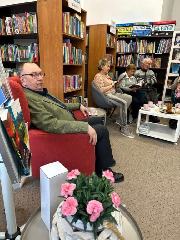 Seniorzy czytają książki w bibliotece