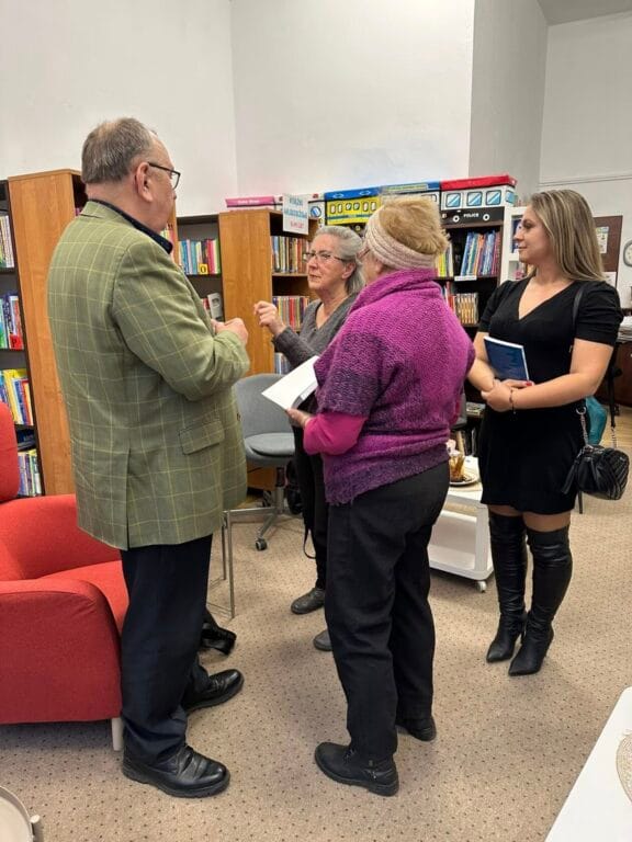 Cztery osoby rozmawiają w bibliotece
