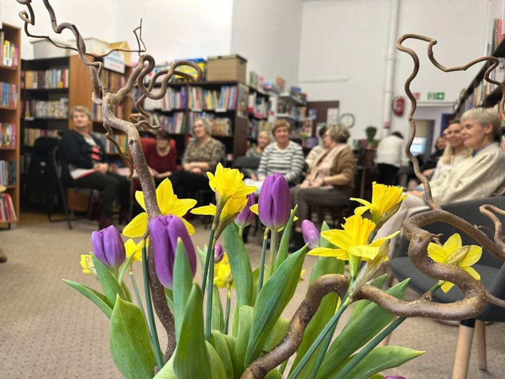 Żółte i fioletowe tulipany w bibliotece, grupa ludzi.