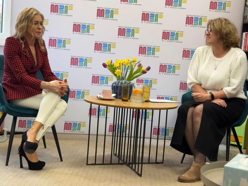 Dwie kobiety rozmawiają w bibliotece przy stoliku