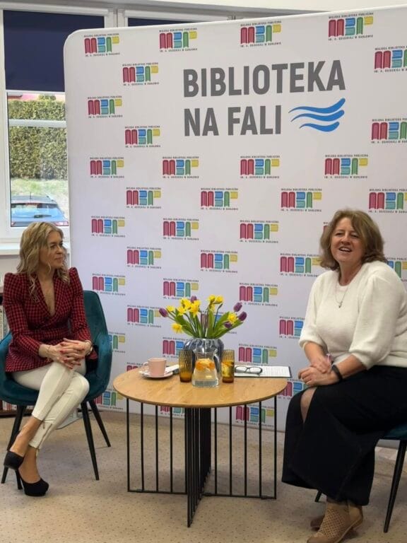 Dwie kobiety rozmawiają przy stole w bibliotece