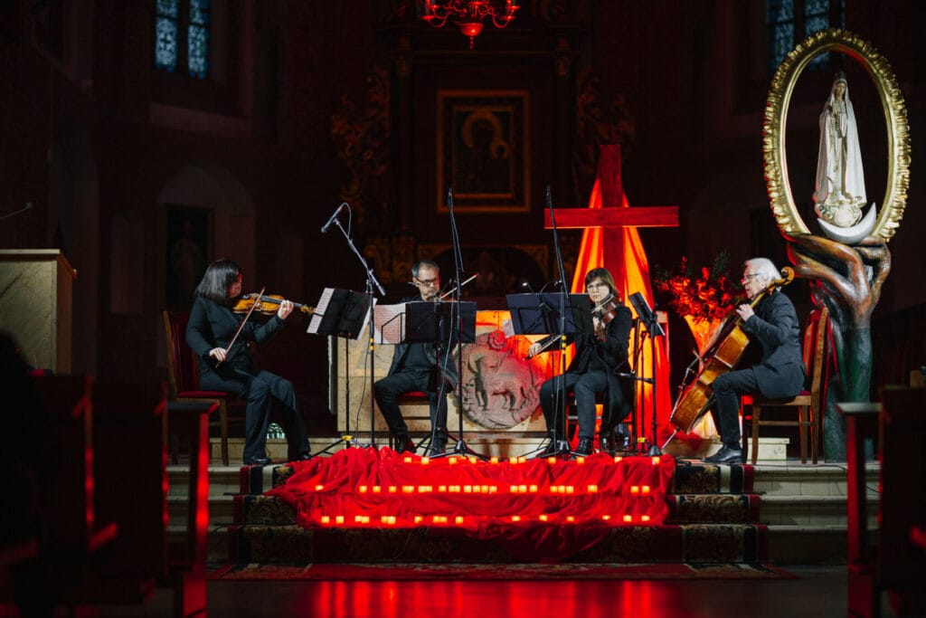 Kwartet smyczkowy gra w kościele przy oświetlonym krzyżu