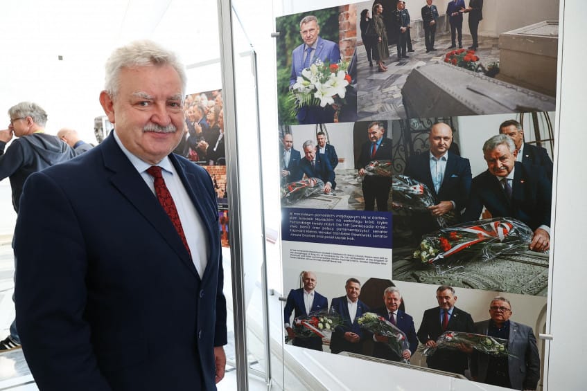 Starszy mężczyzna przystaje do wystawy zdjęć z ceremonii.