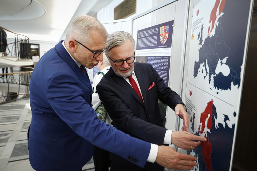 Dwóch mężczyzn w garniturach analizuje mapy na wystawie