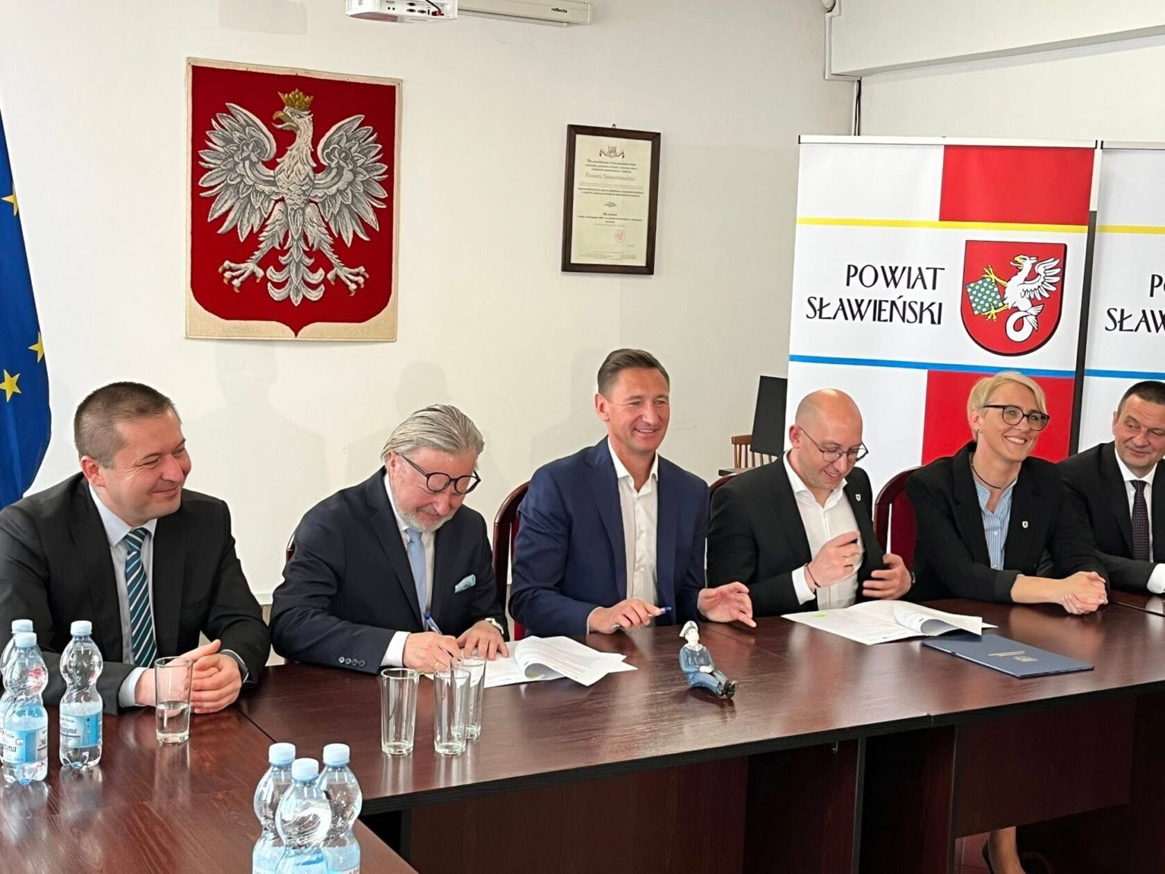 491999179_9553436488104691_4781497832552509891_n Osoby podpisujące dokumenty w urzędzie, godło Polski w tle