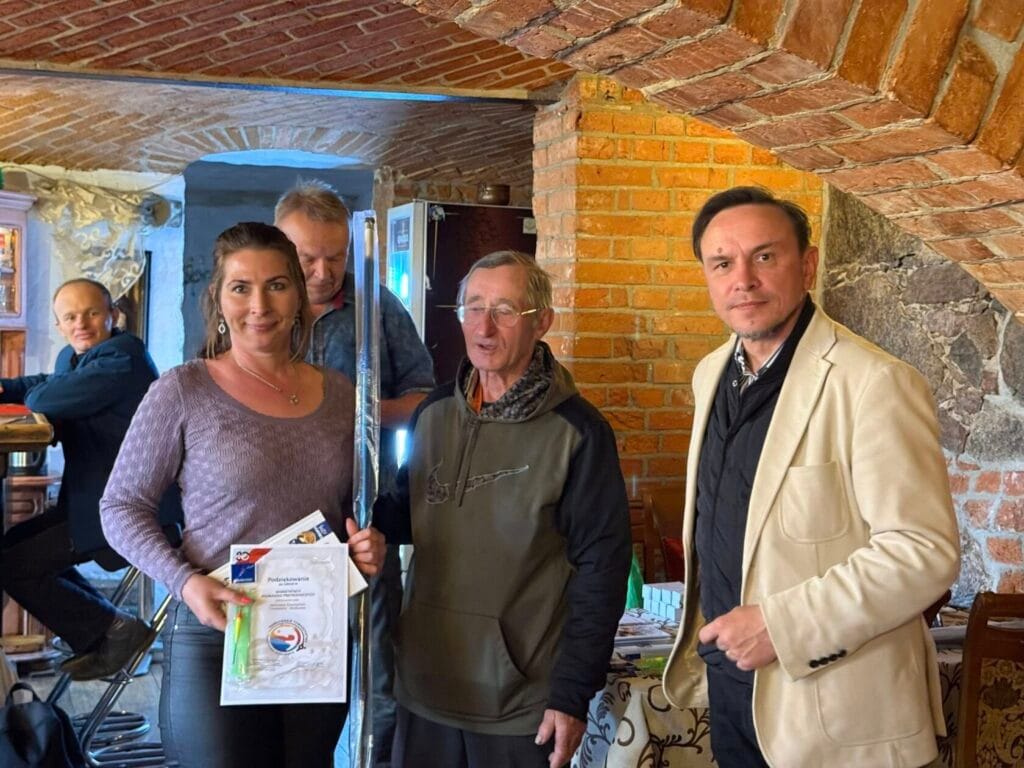 Grupa pięciu osób w ceglanej restauracji, kobieta trzyma dyplom