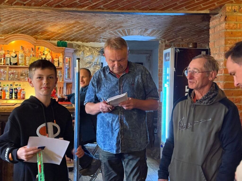 Grupa ludzi w pubie, mężczyzna czyta z notatnika