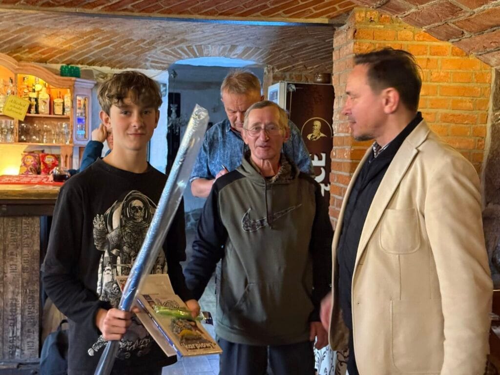 Młody mężczyzna z mieczem w zabytkowym wnętrzu z mężczyznami