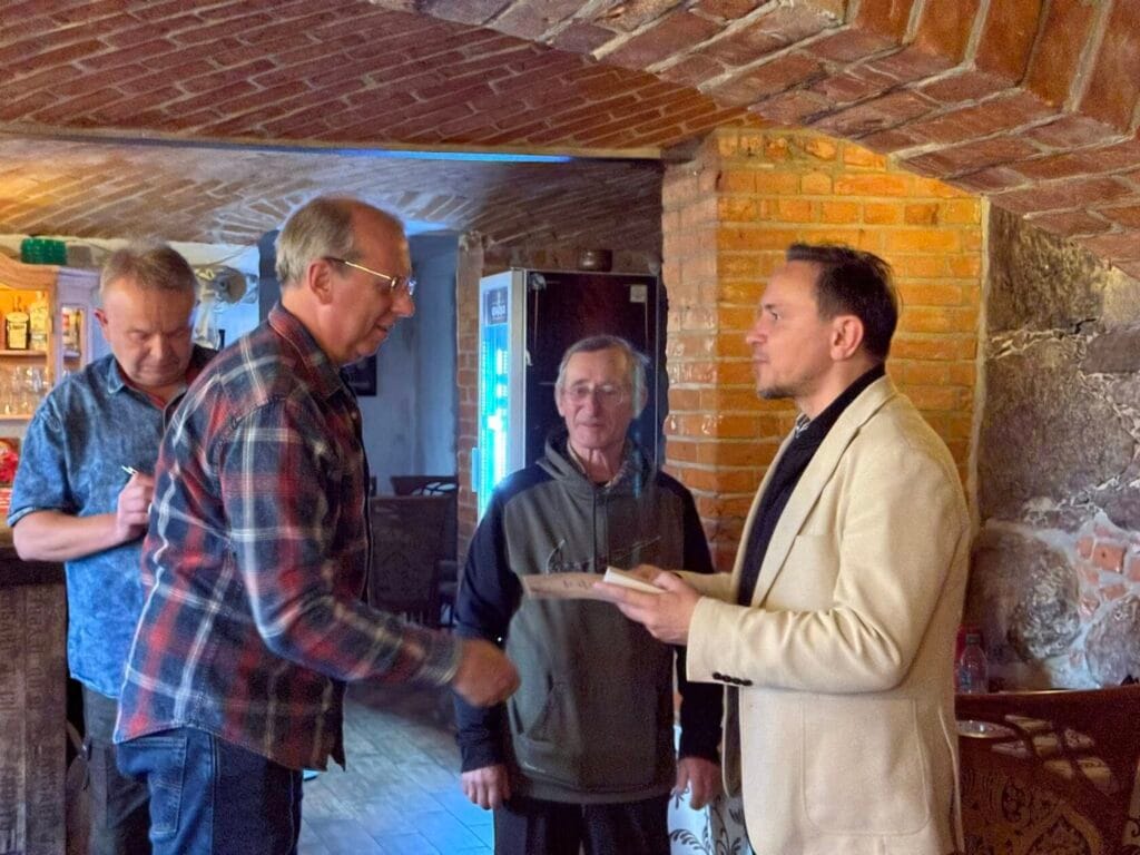 Czterej mężczyźni rozmawiają w rustykalnym wnętrzu