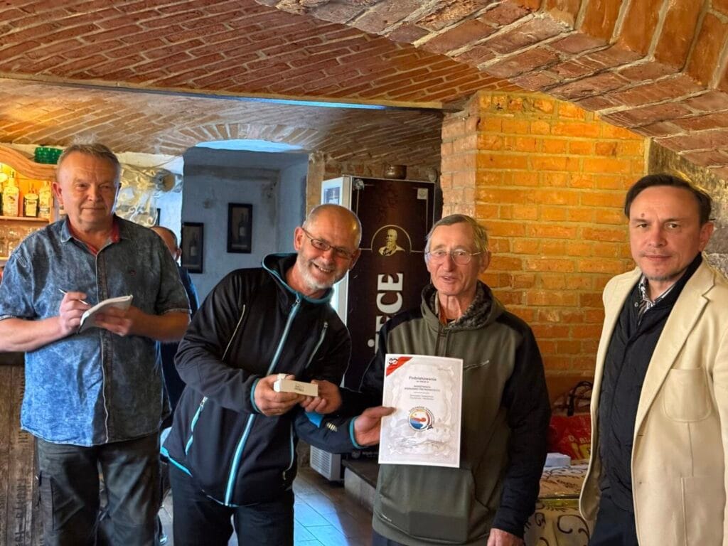 Czterech mężczyzn prezentuje certyfikat w ceglanej piwnicy