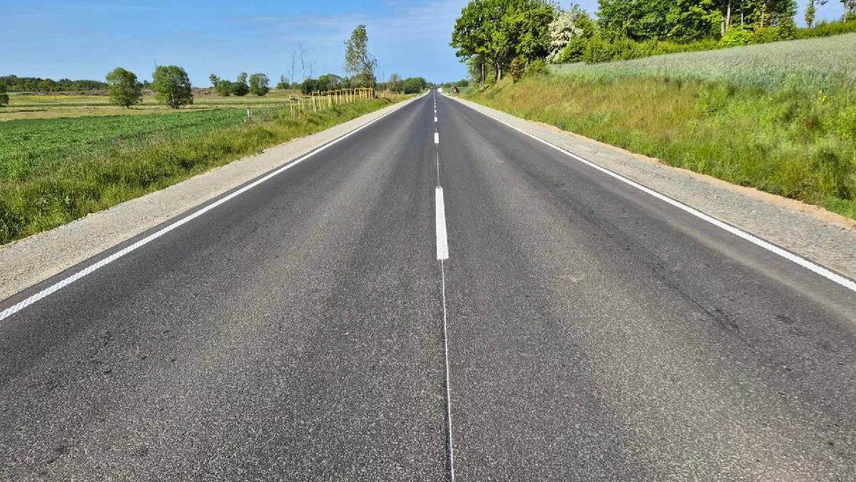 498239044_1103369565150100_5694180810088857769_n Prosta asfaltowa droga otoczona zielenią.