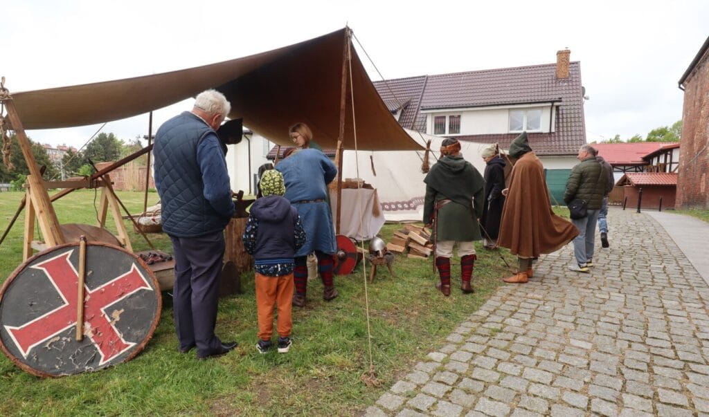 Ludzie w strojach historycznych przy średniowiecznym namiocie.