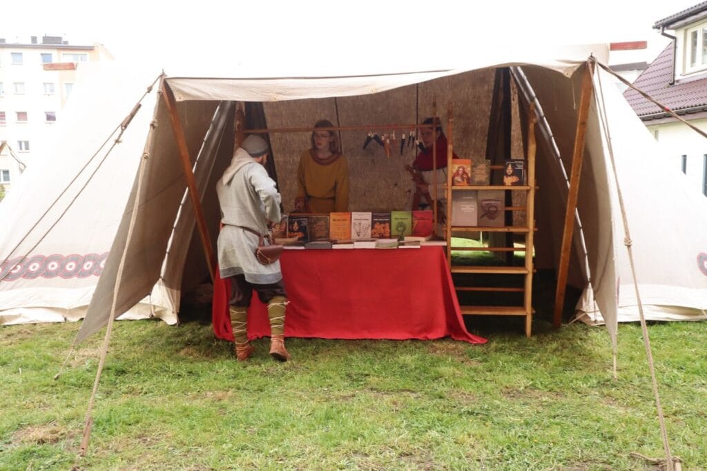 Osoby w historycznych strojach przy stoisku z książkami