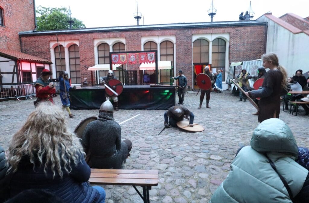 Rekonstrukcja bitwy średniowiecznej na zamkowym dziedzińcu