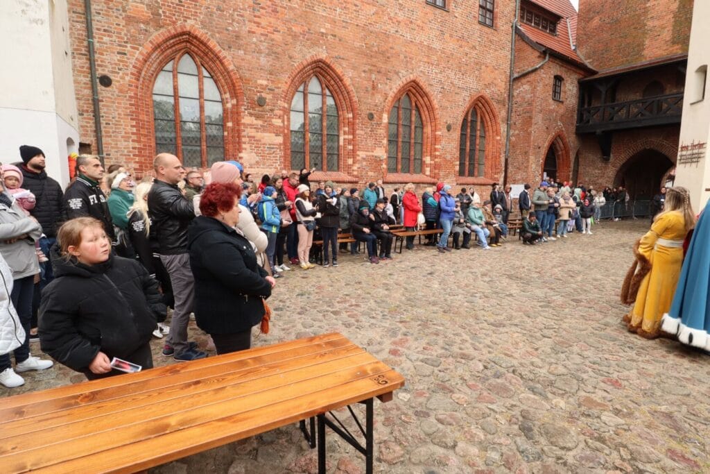 Tłum ludzi słuchających prezentacji na zamkowym dziedzińcu
