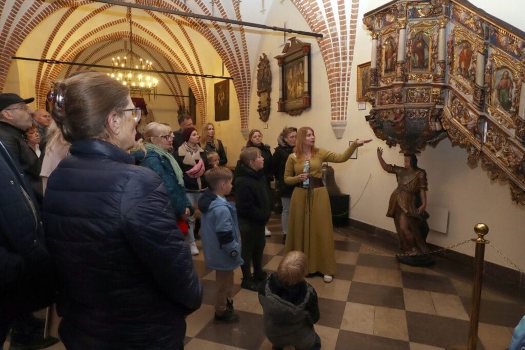 Przewodniczka oprowadza grupę osób po historycznym muzeum