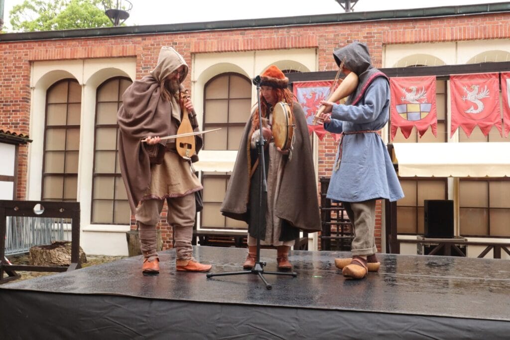 Aktorzy w średniowiecznych strojach grają na instrumentach