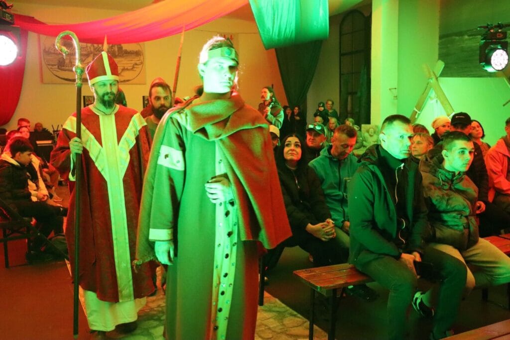 Scena teatralna z aktorami w historycznych strojach.