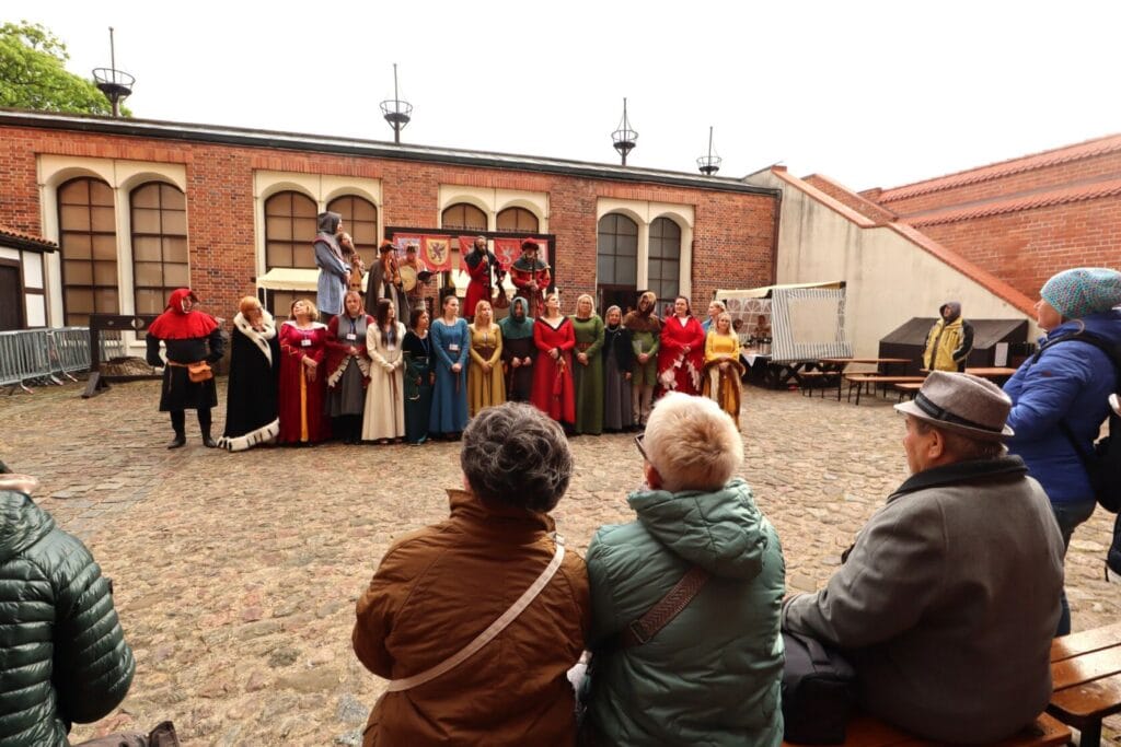 Widzowie obserwujący średniowieczny występ na dziedzińcu