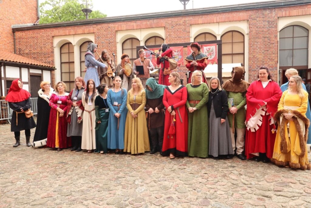 Grupa osób w strojach średniowiecznych na festiwalu historycznym