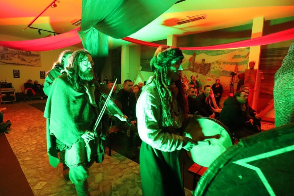 Osoby w historycznych strojach grają na instrumentach