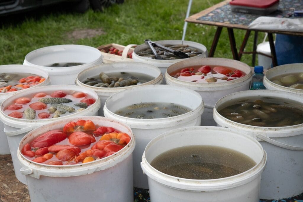 Wiadra z rybami i warzywami na zewnątrznym straganie.