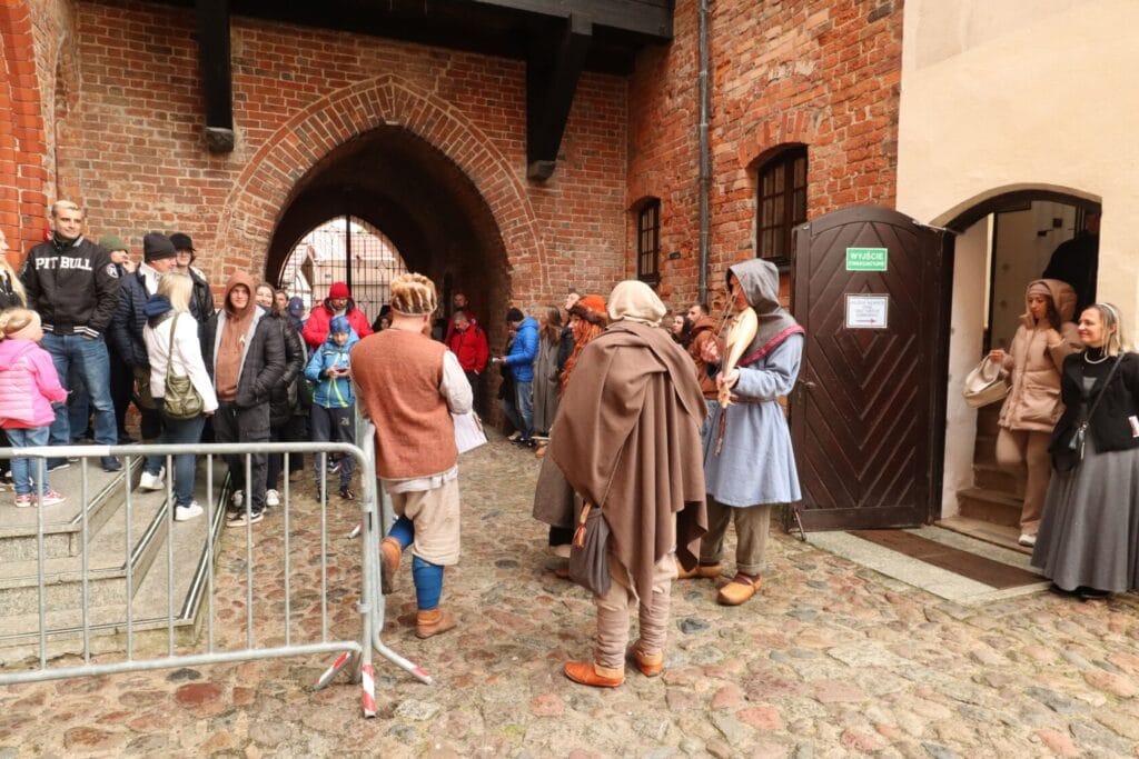 Ludzie w strojach historycznych przy zamkowej bramie